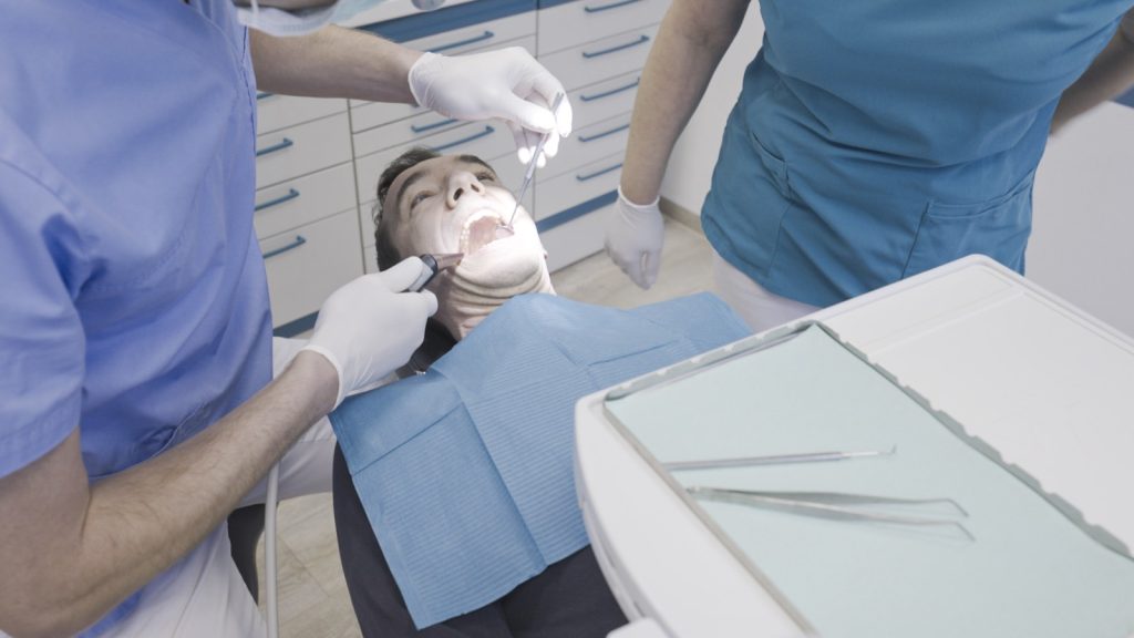 Zahnarzt und Assistenz behandeln eine Patientin am Behandlungsstuhl