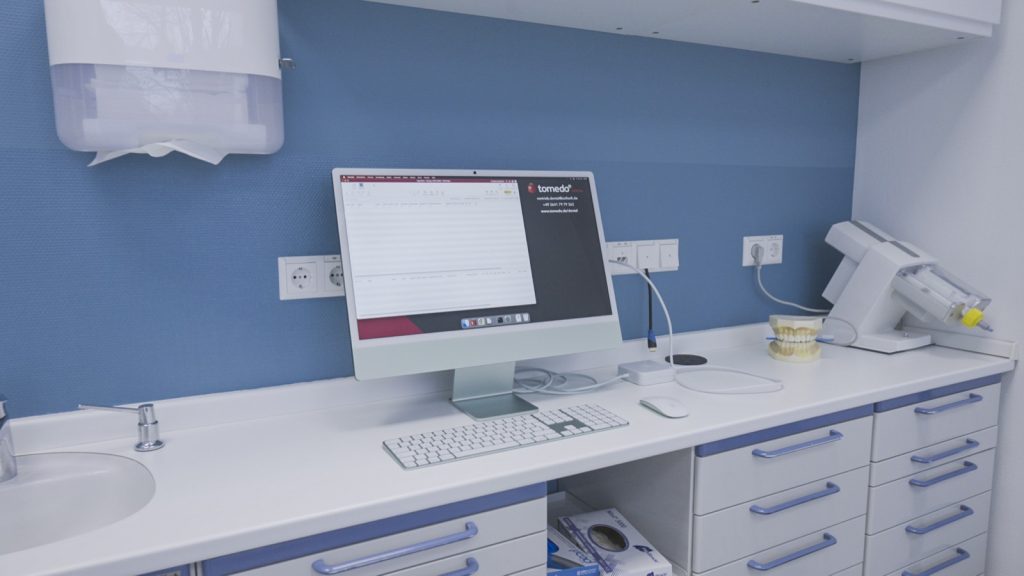 Arbeitsplatz in der Zahnarztpraxis mit geöffneter Praxissoftware tomedo.Dental auf einem iMac
